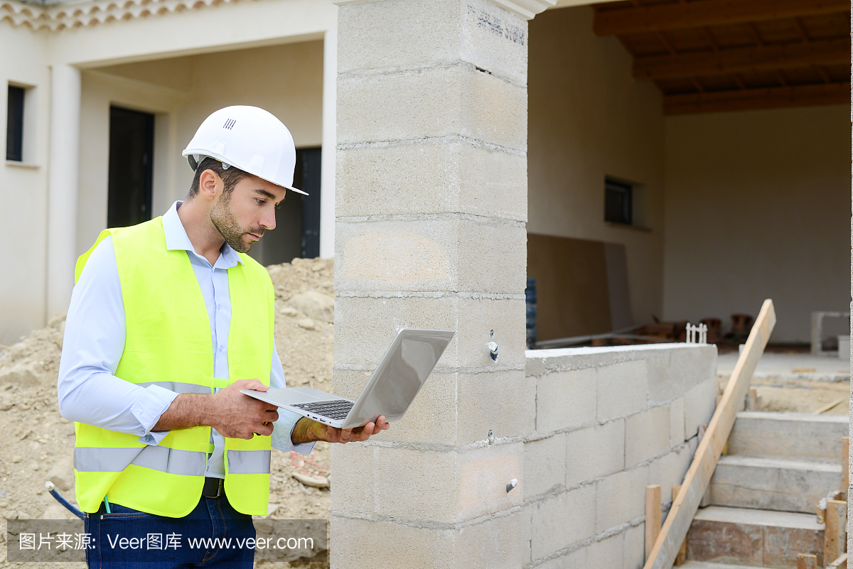 英俊的年輕人工頭建筑師監(jiān)督一個新房子建筑工地